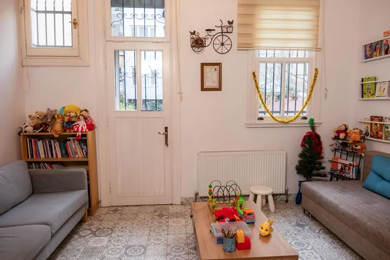 Bahçe kapısına açılan, kitaplıklı ve oyuncaklı karşılama salonu