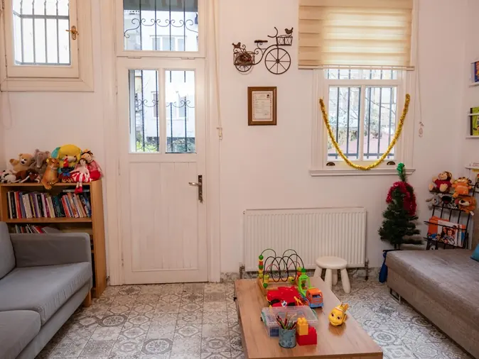 Bahçe kapısına açılan, kitaplıklı ve oyuncaklı karşılama salonu
