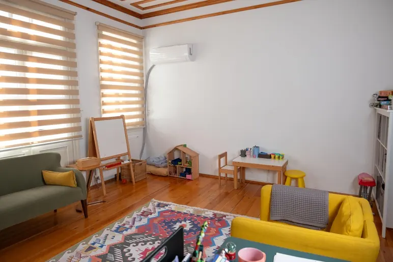 Kilim serili, sarı kanepeli ve şövaleli geniş terapi odası