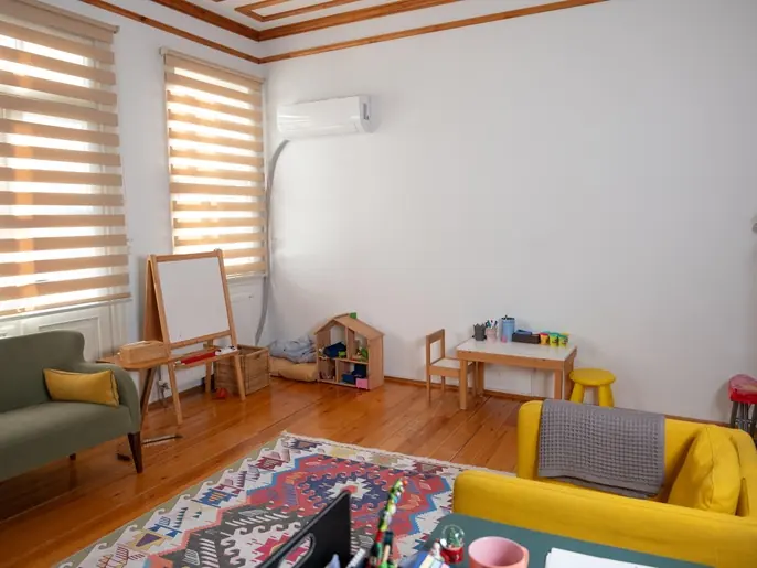 Kilim serili, sarı kanepeli ve şövaleli geniş terapi odası